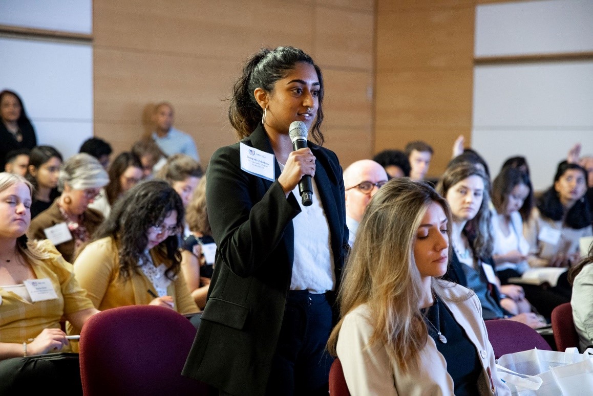 A UNA-USA member stands to speak into a microphone during a Global Leadership Summit consultation